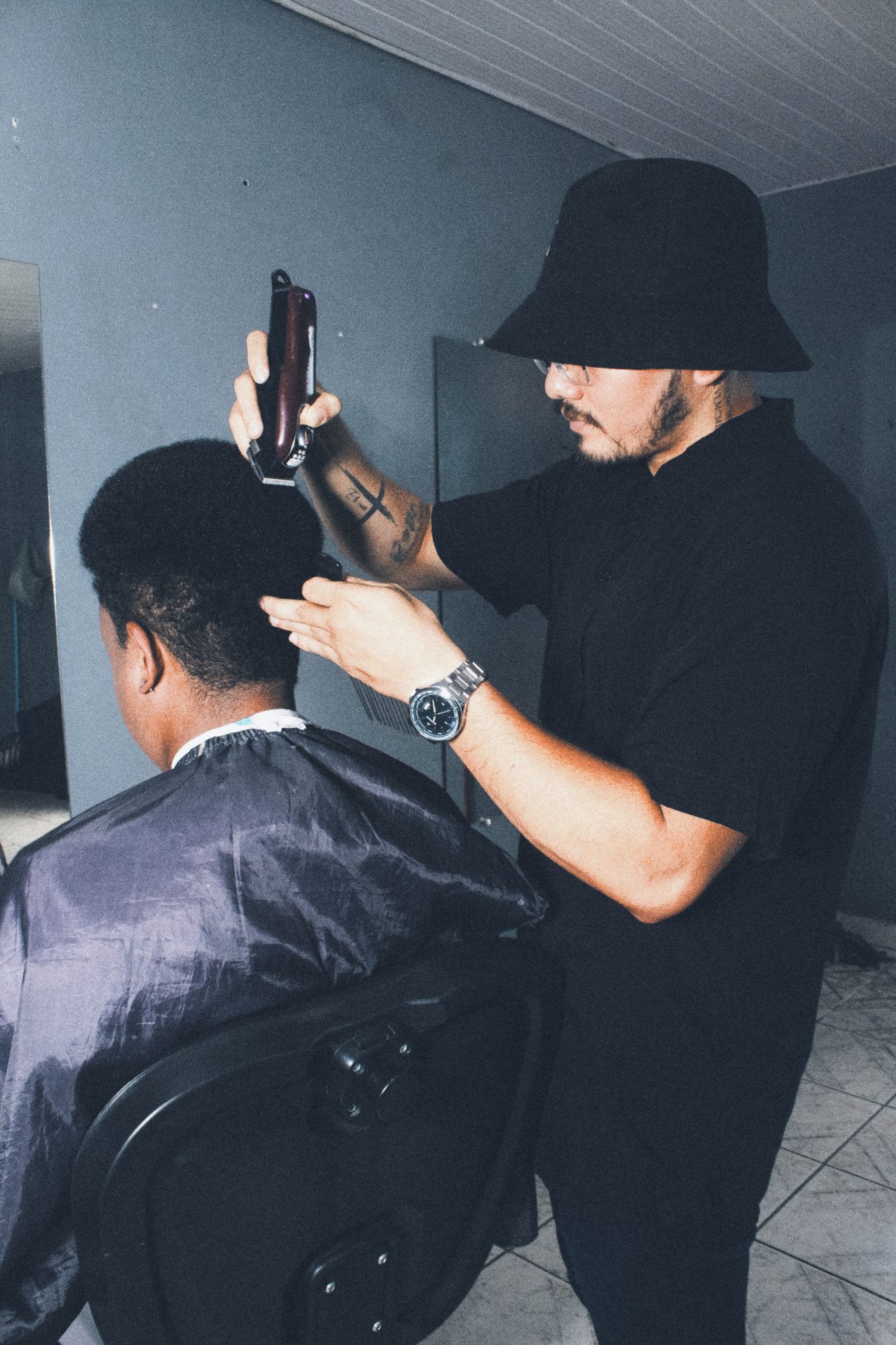 Barbeiro de bairro cortando o cabelo de um cliente adulto, de costas