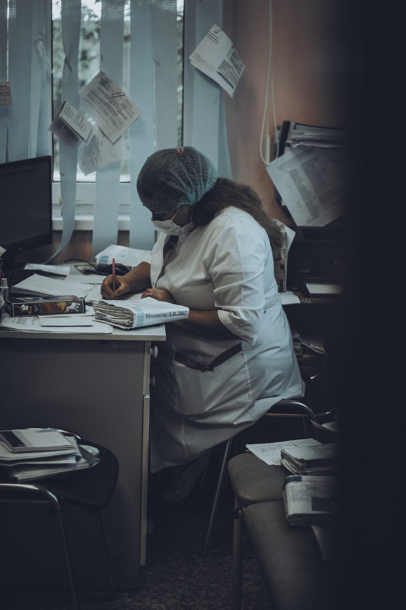 Profissional de saúde preenchendo papéis no consultório, luz de janela