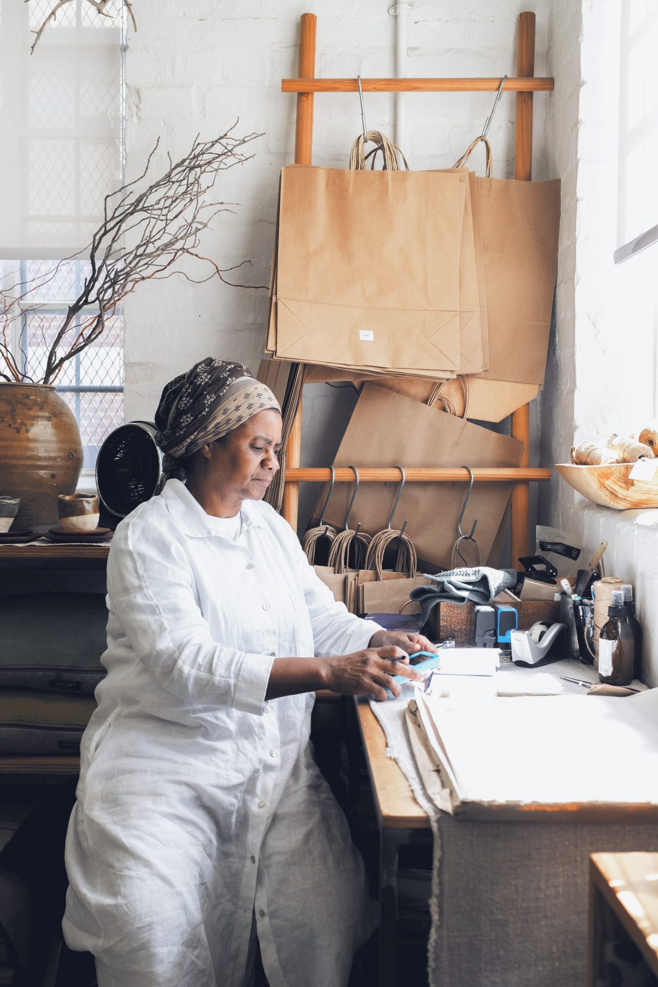 Dona de ateliê trabalhando na bancada, luz natural