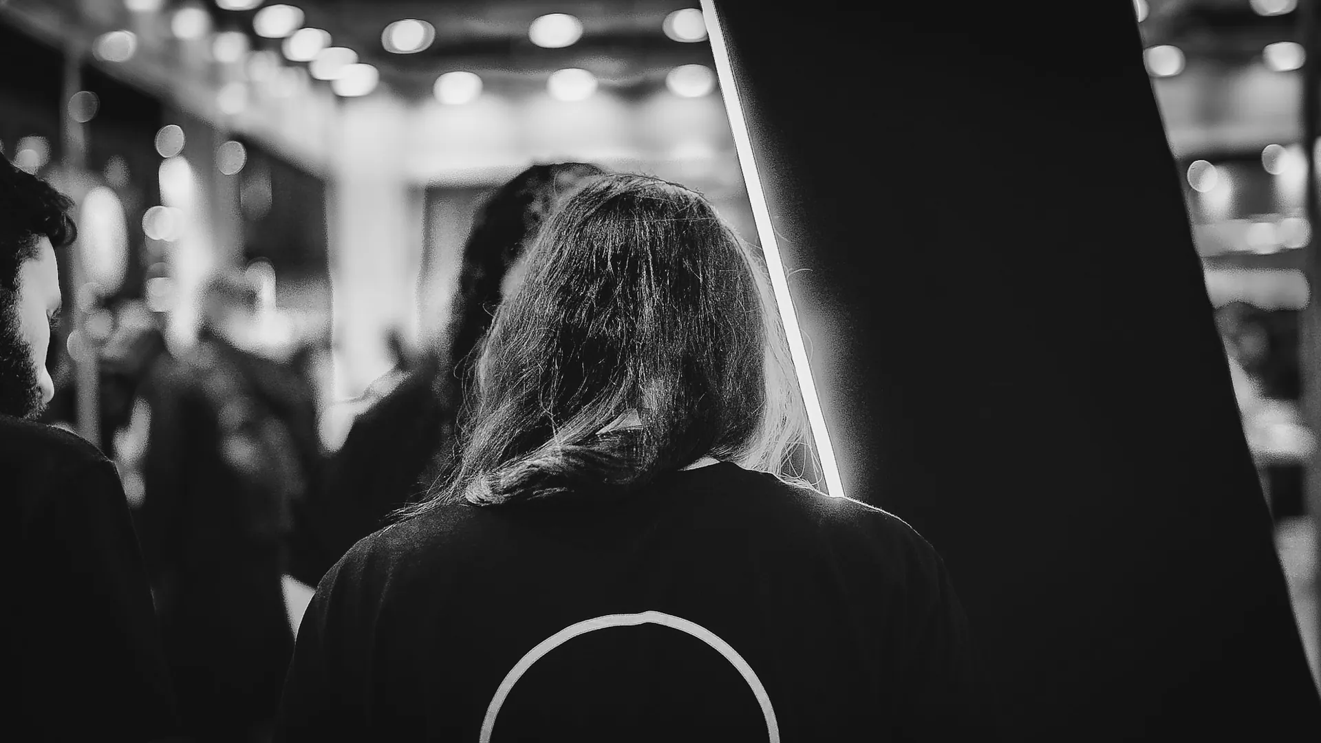 Pessoa de costas vestindo camiseta com o símbolo da The VOID no corredor da convenção