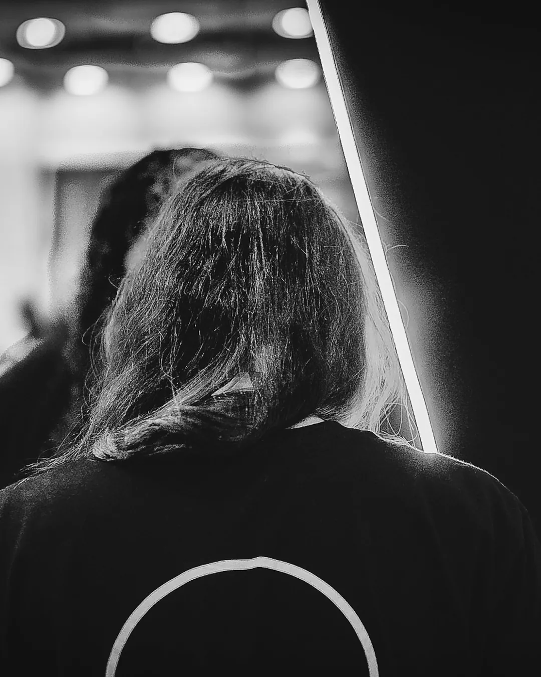 Pessoa de costas vestindo camiseta com o símbolo da The VOID no corredor da convenção