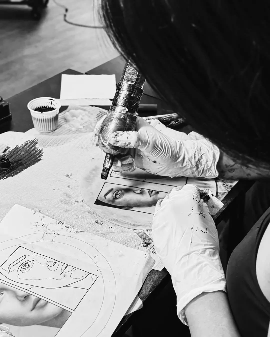Aluna de luvas tatuando retrato realista em pele sintética na bancada da escola