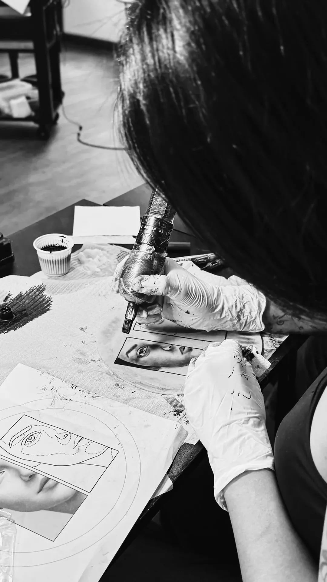 Aluna de luvas tatuando retrato realista em pele sintética na bancada da escola