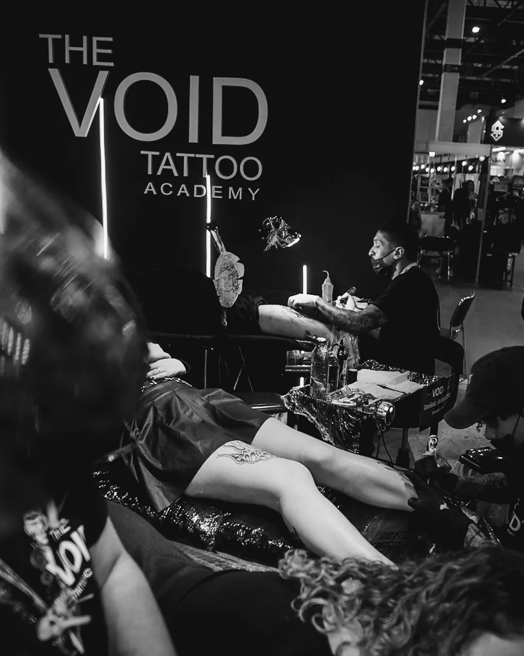 Estande da The VOID com logotipo grande e várias sessões de tatuagem acontecendo na convenção