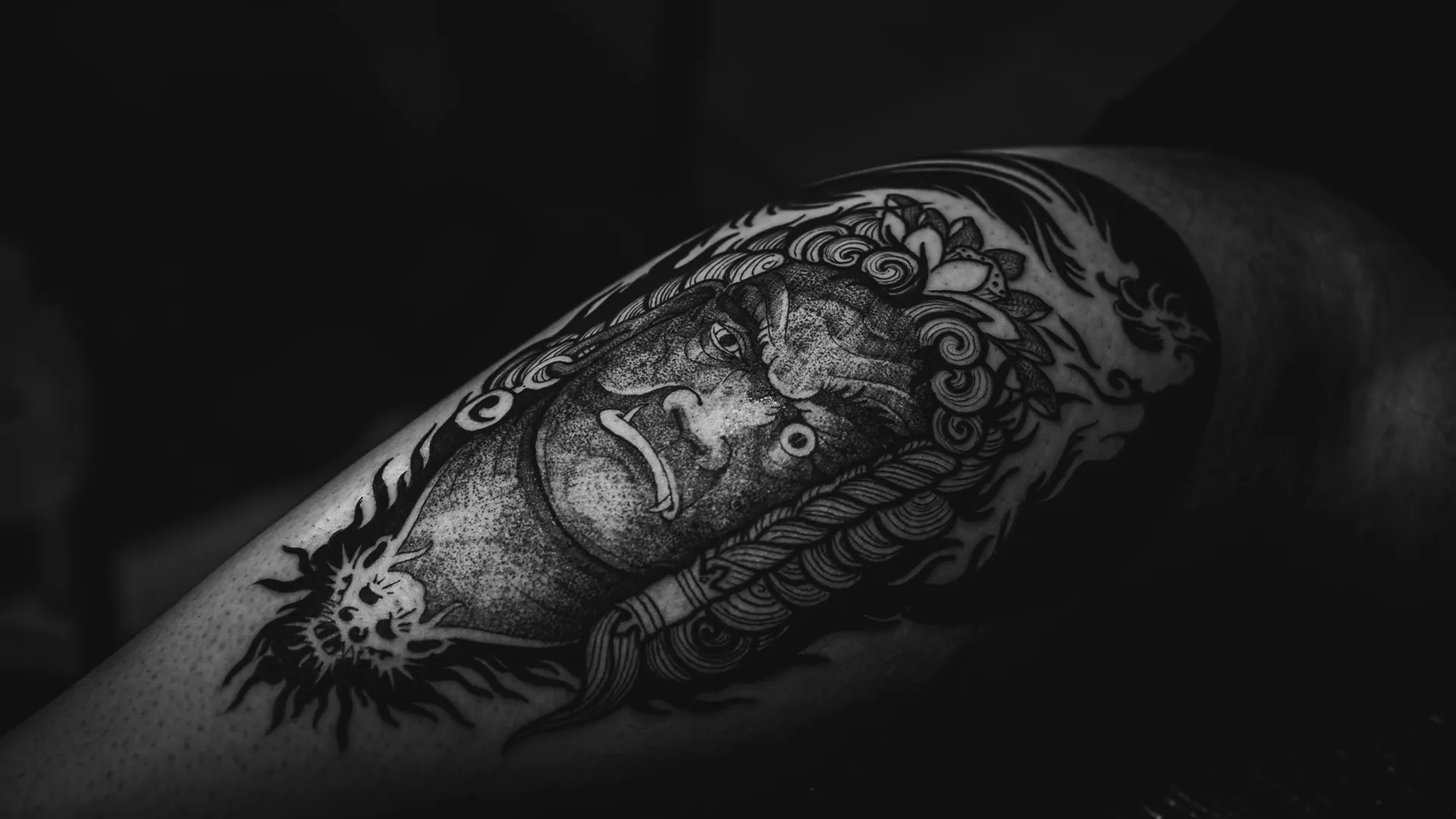 Close de antebraço com tatuagem blackwork sob luz lateral dramática