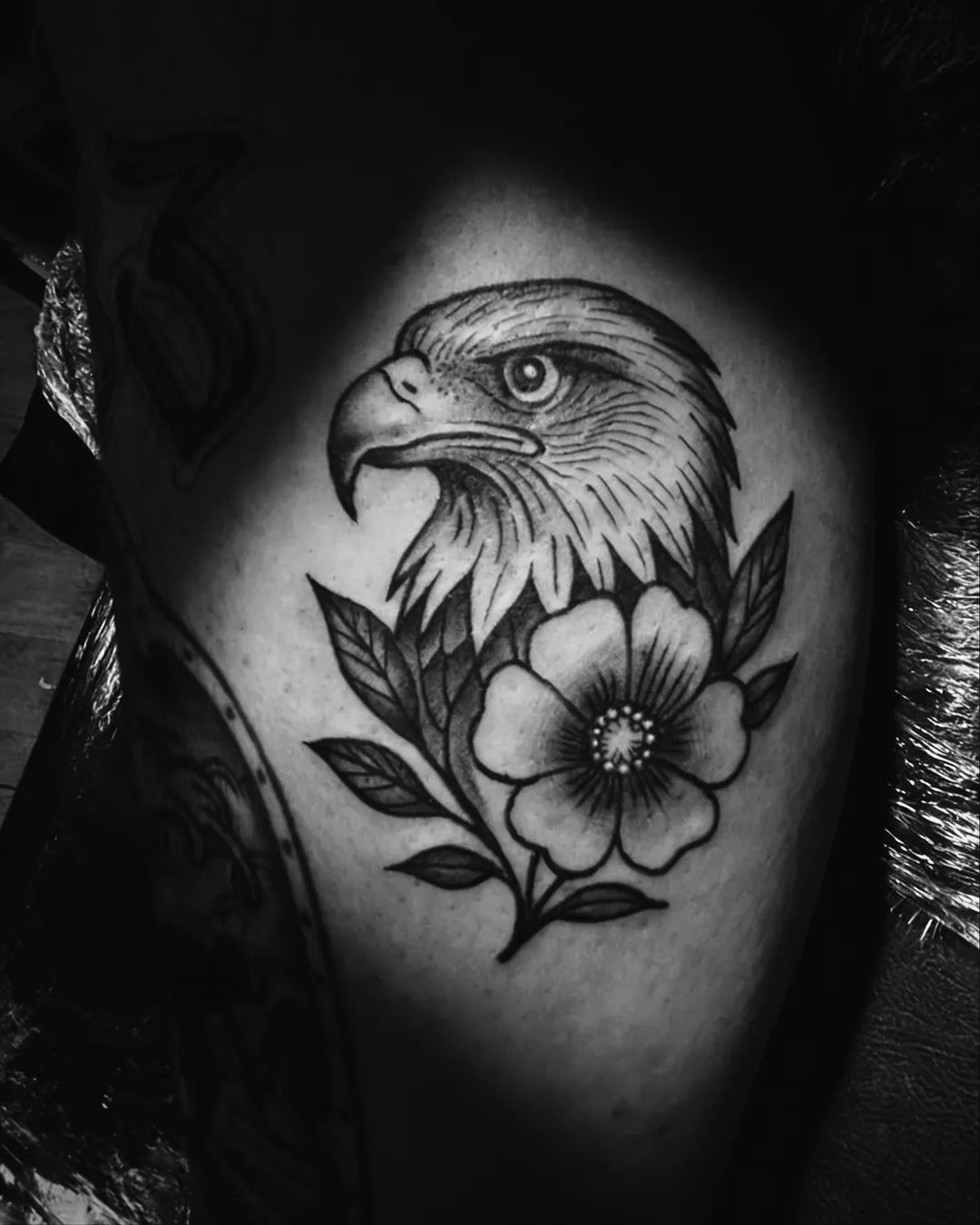 Águia com flor em estilo tradicional tatuada em preto e cinza