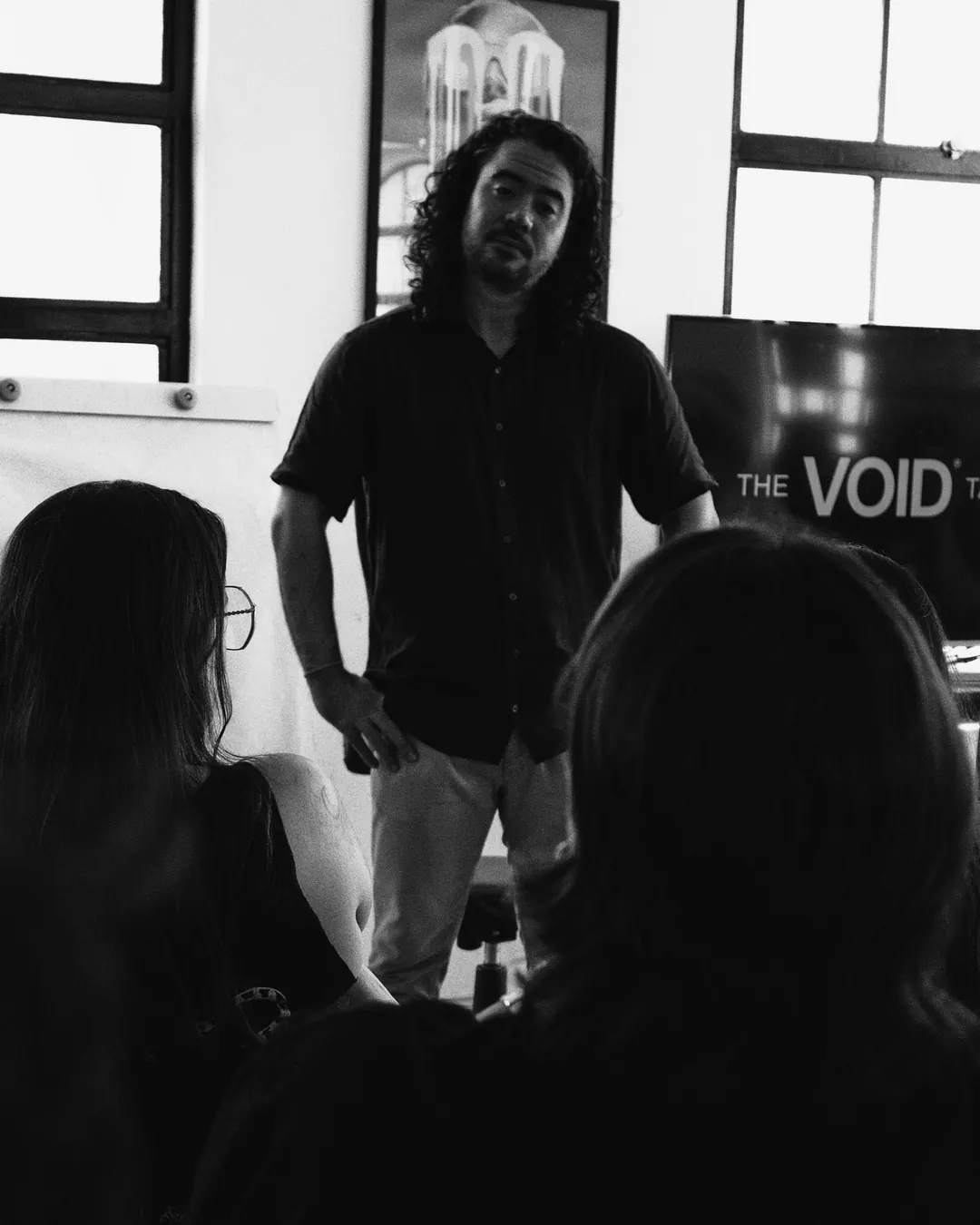 Professor Lucas Tengan em pé falando para alunas sentadas na sala da escola The VOID