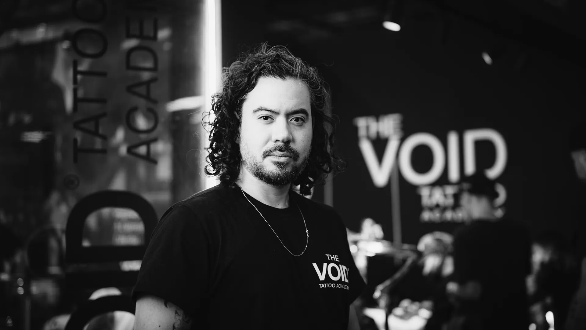 Retrato de Lucas Tengan no estande da The VOID com letreiro iluminado ao fundo