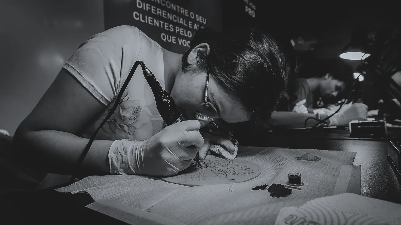 Aluna de óculos e luvas tatuando pele sintética no duotom Pro, de Sala a Névoa