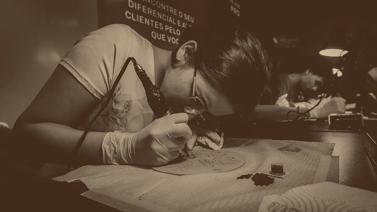 Aluna de óculos e luvas tatuando pele sintética no duotom Start, de Café a Areia